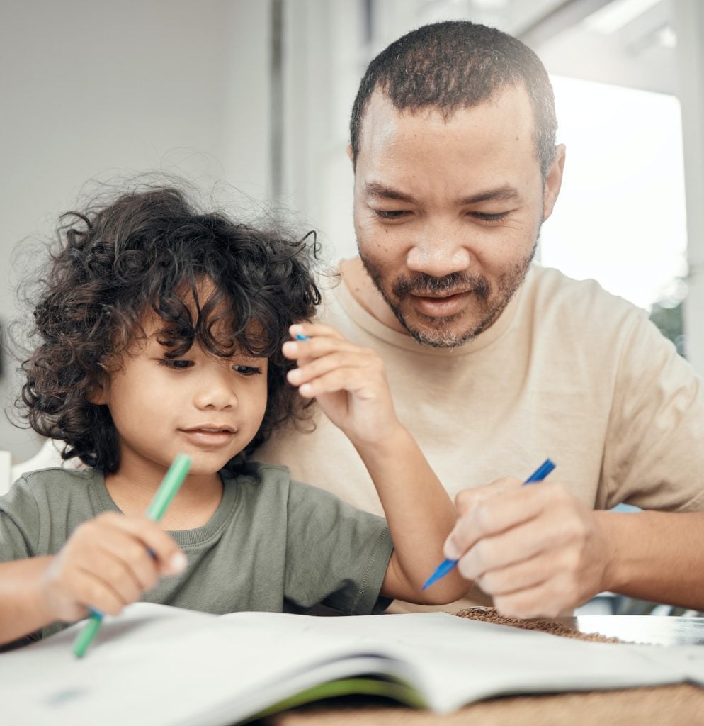 Your drawing is almost as good as mine, dad. Shot of a man helping his son with his homework.